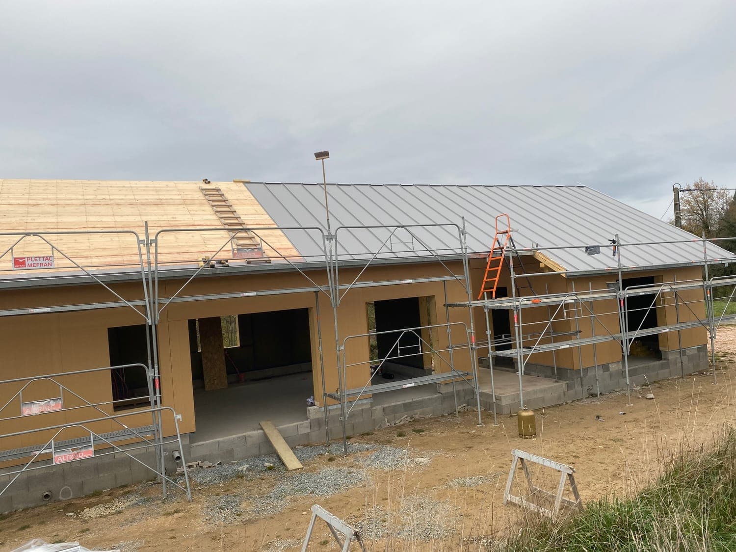 Couverture bac acier en cours de pose sur une maison ossature bois au Mayet-de-Montagne