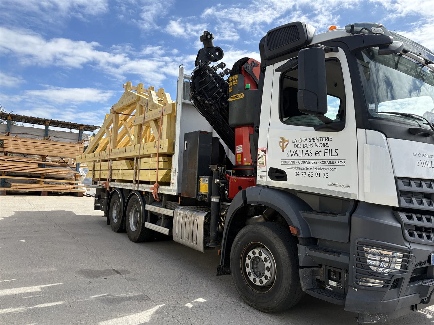 Ferme de charpente traditionnelle taillée à l'atelier, chargée et sanglée sur le camion-grue, prête à être livrée